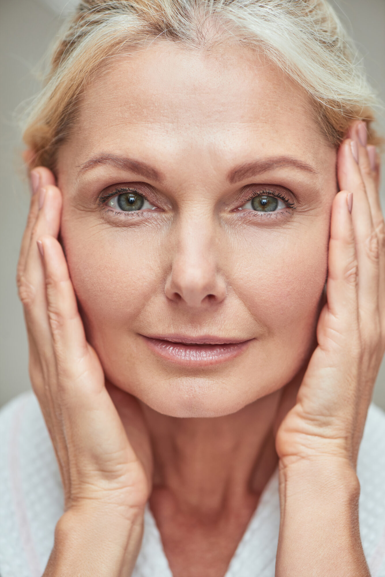 Middle aged caucasian woman with hands near face traitement des rides par le laser Clinique Rivoli Massena 2